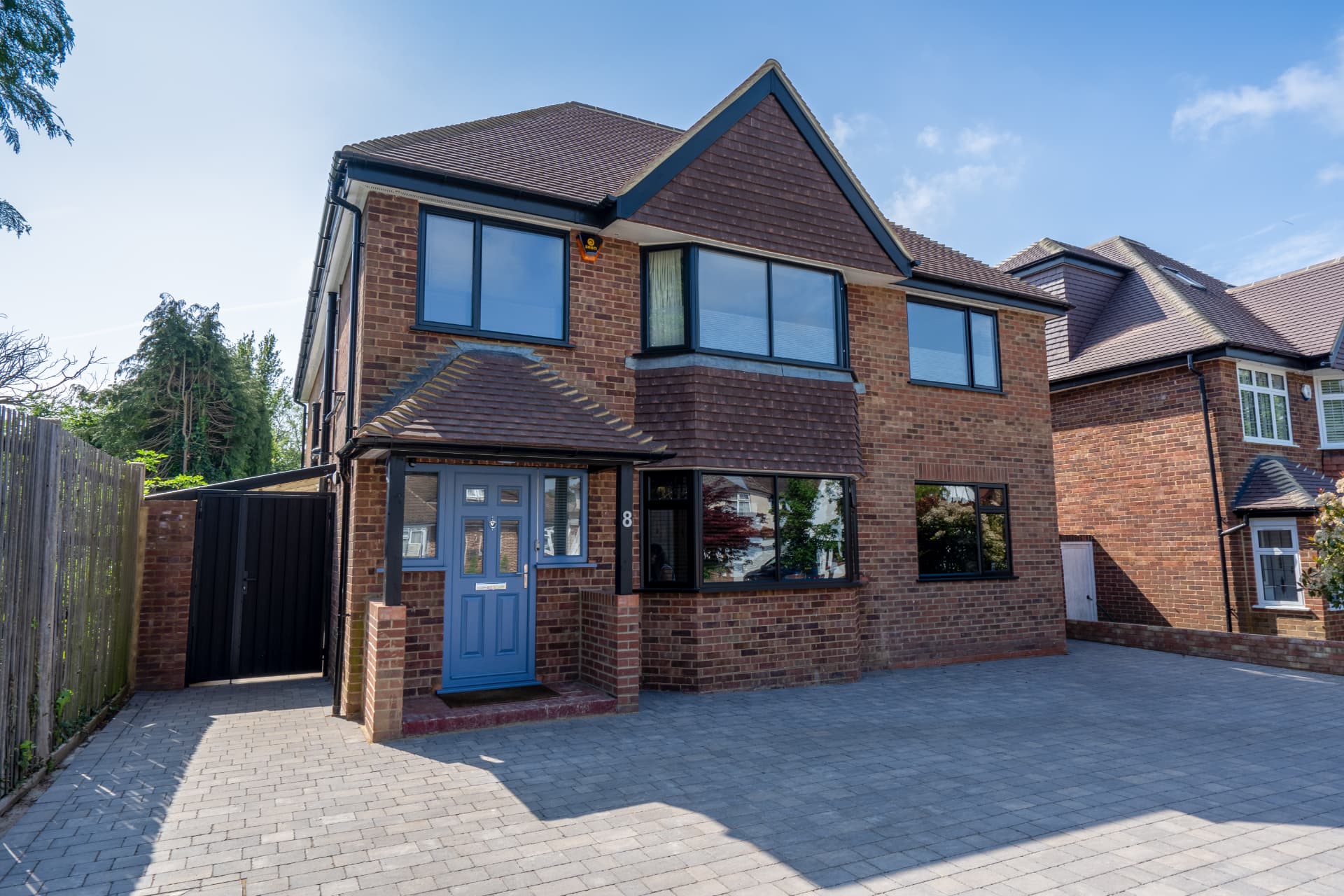 A completed detached house with a blue front door and new brick porch
